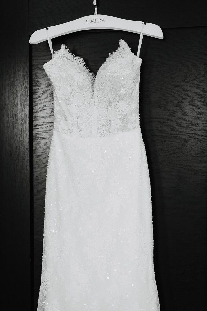 weißes Brautkleid hängt vor schwarzem Hintergrund