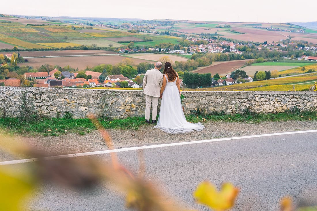 Hochzeitspaar mit dem rücken zur Kamera Händchen haltend blickt gemeinsam in die weiten der Landschaft