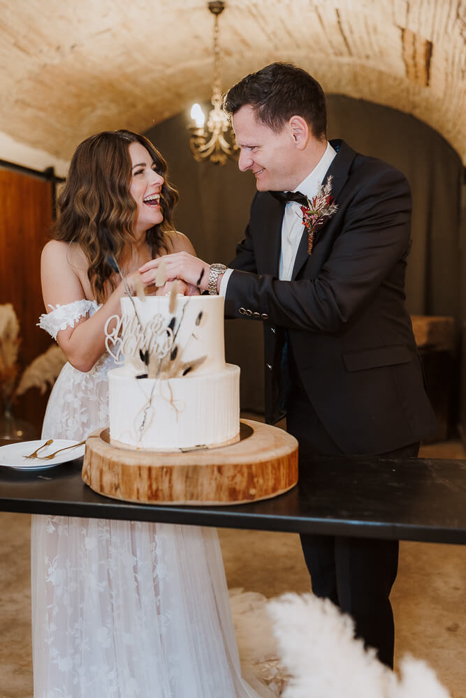 Brautpaar fröhlich beim anschneiden ihrer Hochzeitstorte