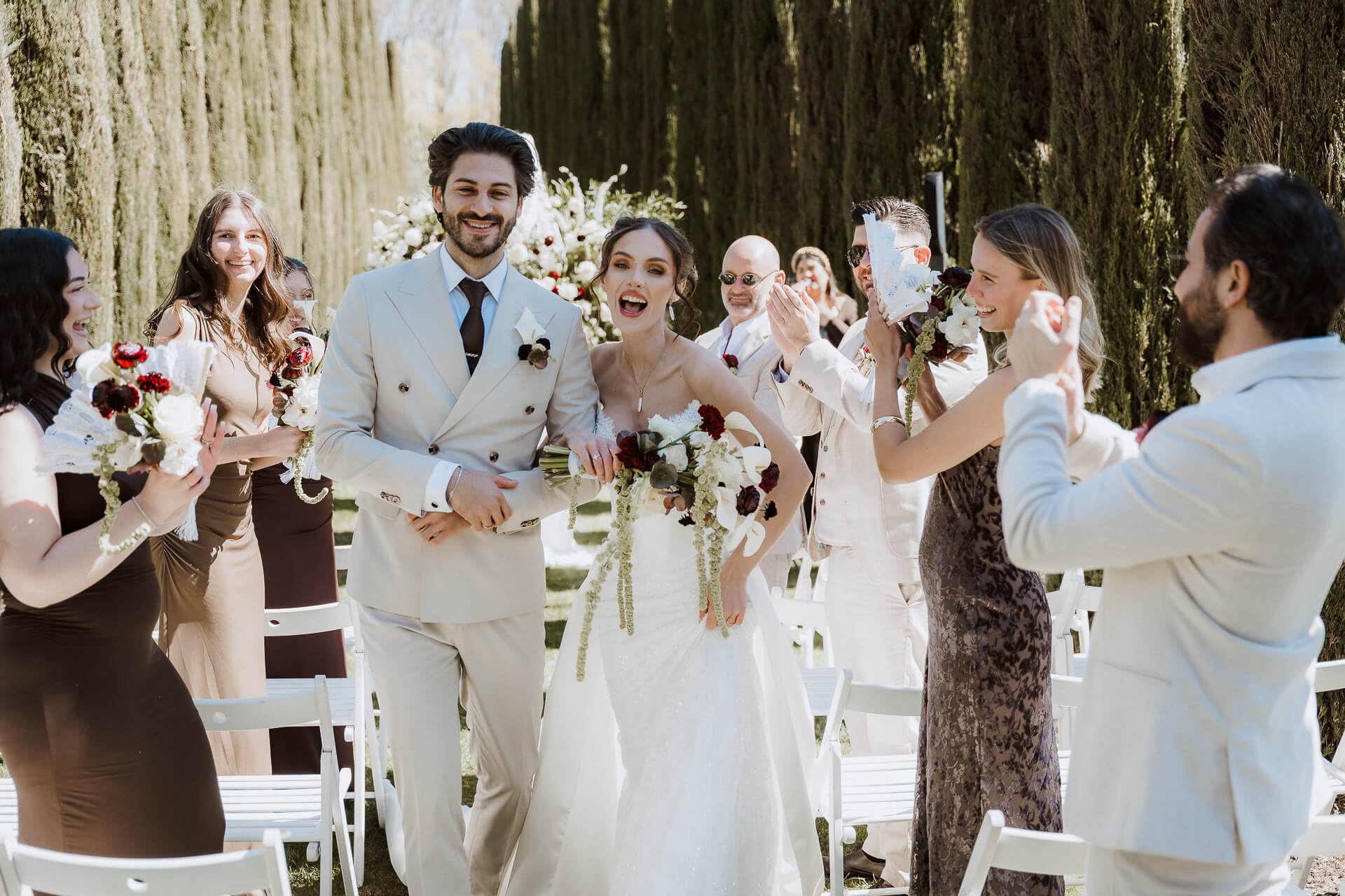 Hochzeitspaar lacht und läuft Hand in Hand beim Auszug direkt nach der Trauung